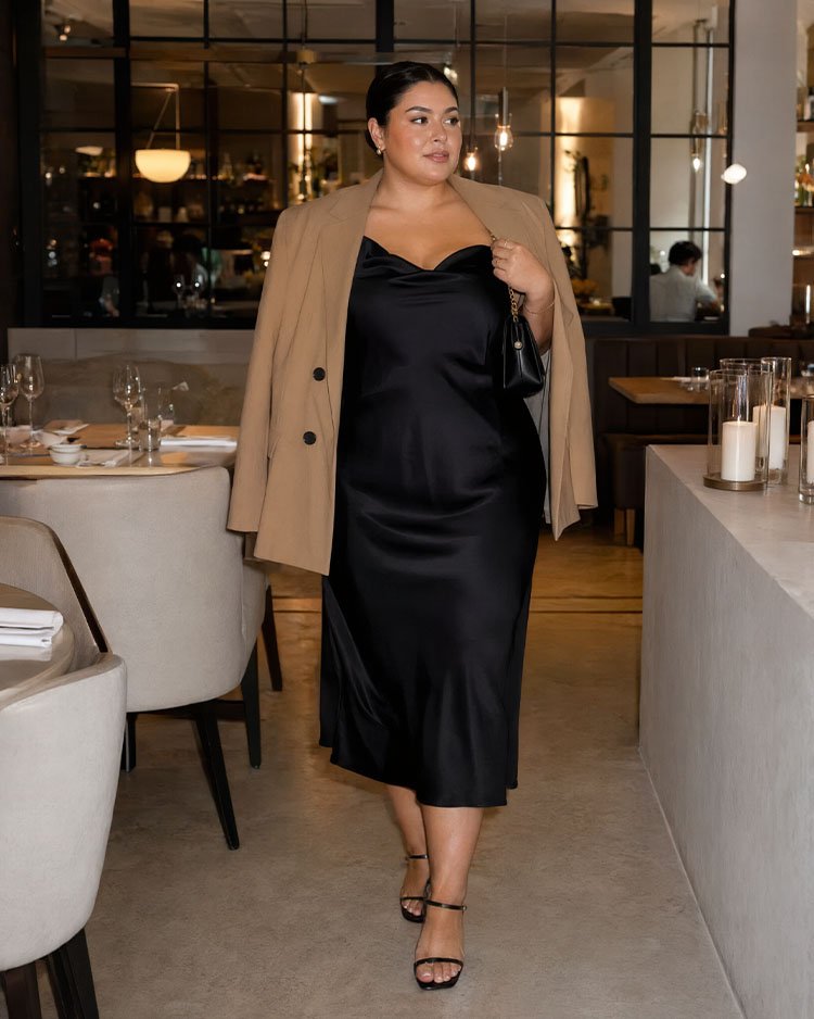 Чёрное атласное платье-комбинация миди plus size с бежевым жакетом и босоножками для праздничного ужина в ресторане.